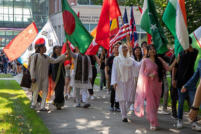 留学生们举着各自国家的国旗，走在毕业典礼游行队伍的最前面.